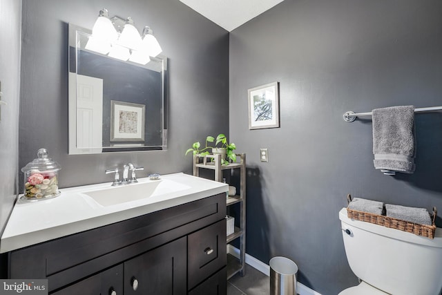 half bath with baseboards, vanity, and toilet