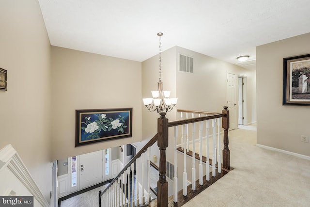 corridor with carpet, visible vents, an upstairs landing, and an inviting chandelier