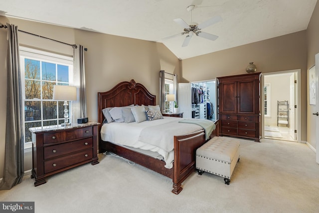 bedroom featuring light carpet, lofted ceiling, ceiling fan, a spacious closet, and a closet