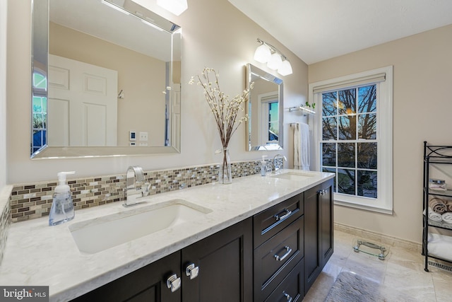 bathroom featuring tasteful backsplash, a sink, baseboards, and double vanity