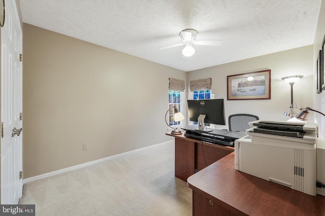 home office featuring light carpet, ceiling fan, a textured ceiling, and baseboards