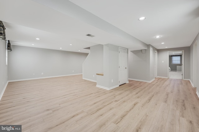 finished below grade area with light wood-style floors, recessed lighting, visible vents, and baseboards