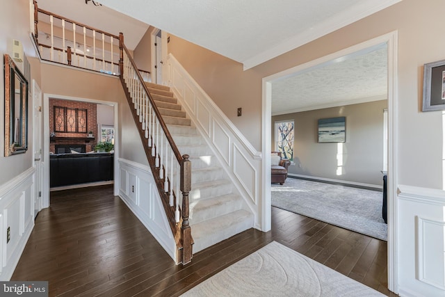 stairs featuring ornamental molding, a decorative wall, a textured ceiling, and hardwood / wood-style flooring