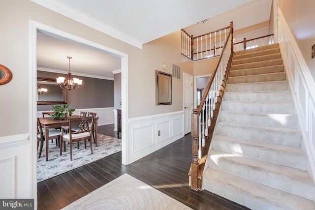 stairway featuring a wainscoted wall, visible vents, ornamental molding, and hardwood / wood-style floors