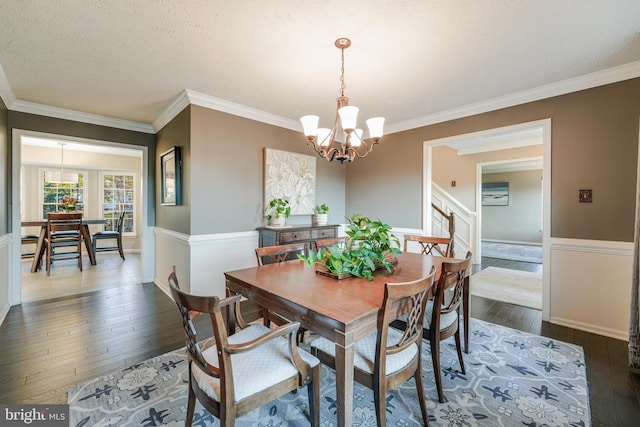 dining space featuring a textured ceiling, dark wood-type flooring, a chandelier, and crown molding