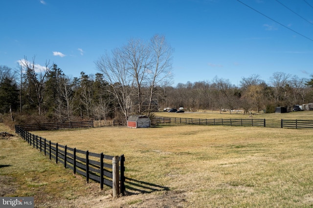 view of yard with an outbuilding, a shed, a rural view, and fence