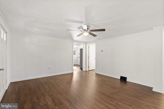 empty room with baseboards, visible vents, ceiling fan, ornamental molding, and wood finished floors