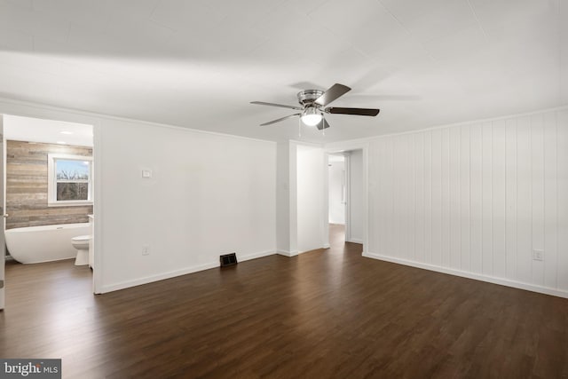 spare room featuring baseboards, a ceiling fan, and dark wood-type flooring