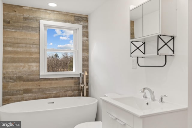 bathroom with wooden walls, a soaking tub, and vanity