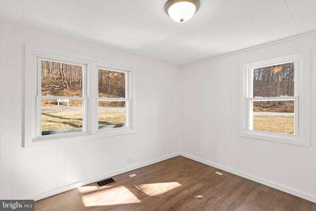 empty room with dark wood-style floors, baseboards, and visible vents