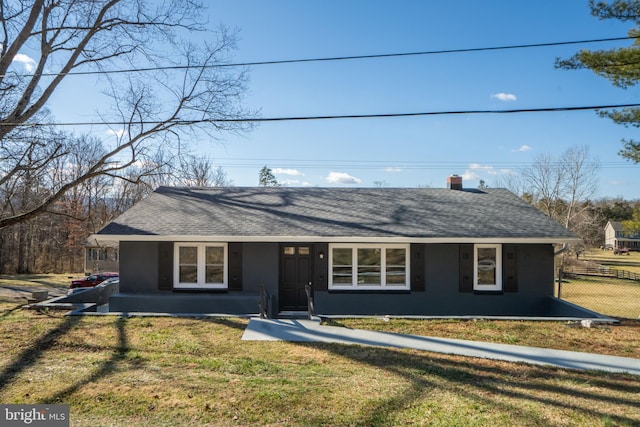 view of front facade featuring roof with shingles, fence, a front lawn, and stucco siding