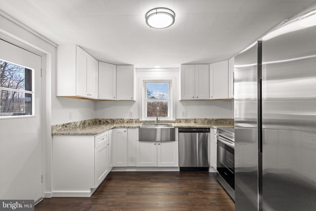 kitchen featuring white cabinets, light stone counters, stainless steel appliances, and dark wood-style flooring