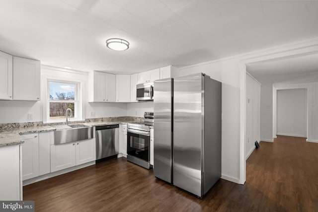 kitchen with appliances with stainless steel finishes, dark wood finished floors, white cabinets, and a sink