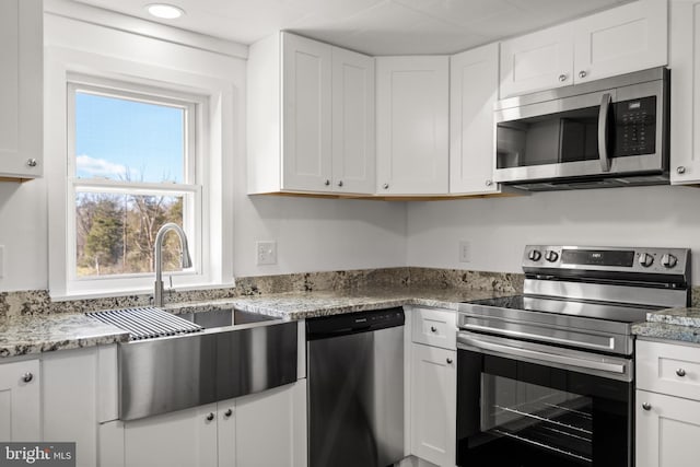 kitchen with stainless steel appliances, a sink, and white cabinets