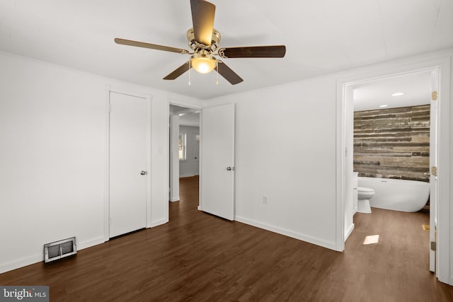 unfurnished bedroom featuring ensuite bathroom, wood finished floors, visible vents, and baseboards