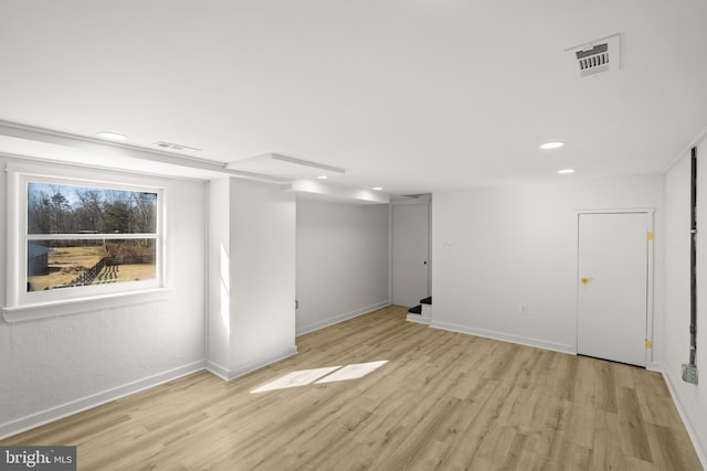 basement featuring light wood-type flooring, visible vents, and baseboards