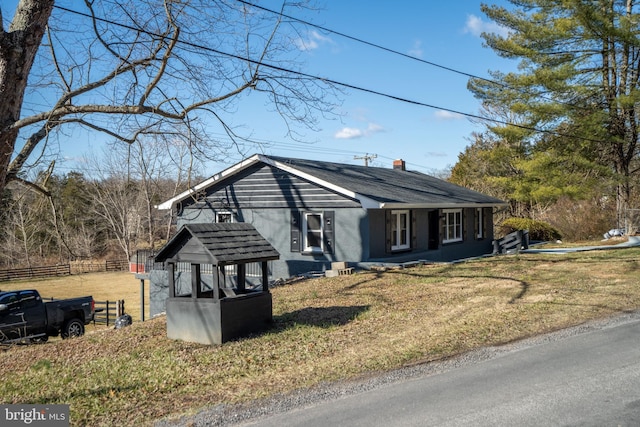 view of front of house featuring a chimney, a front yard, and fence