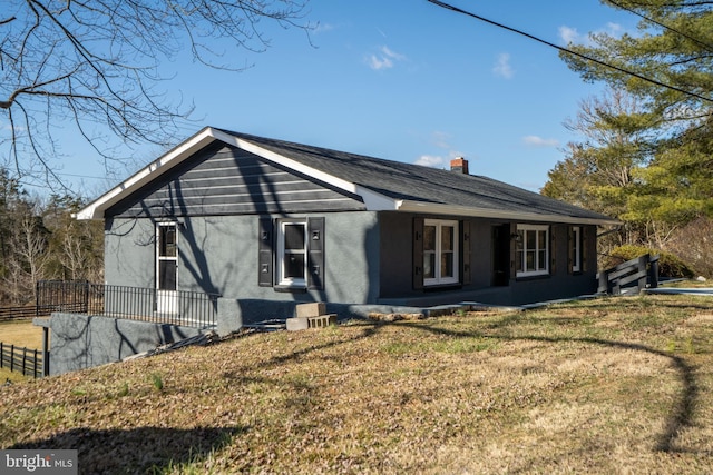 view of front of house featuring a front lawn, a chimney, fence, and stucco siding