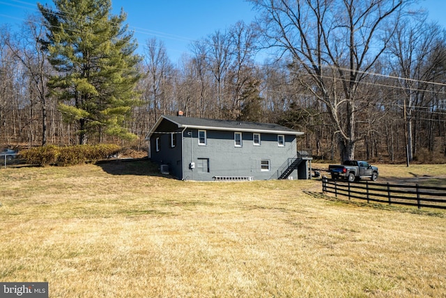 view of property exterior featuring a yard, stairway, and fence