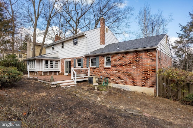 rear view of property with a chimney, a deck, central AC, and brick siding