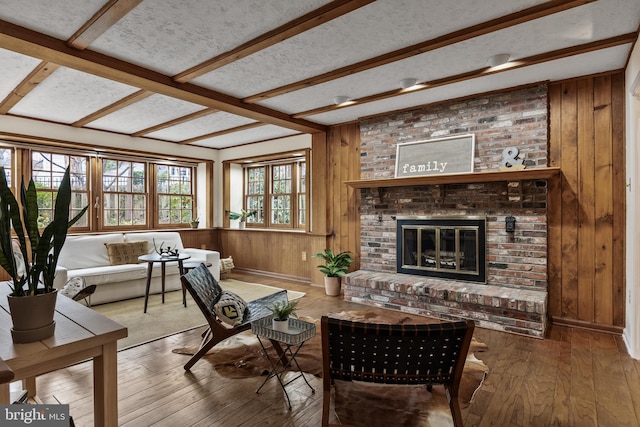 living room featuring wood walls, wood-type flooring, a fireplace, and a textured ceiling