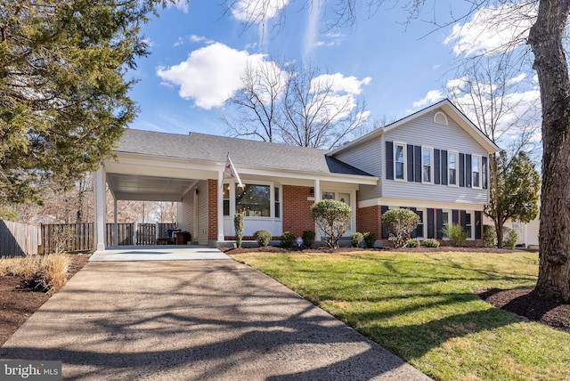 split level home featuring brick siding, concrete driveway, a front yard, fence, and an attached carport