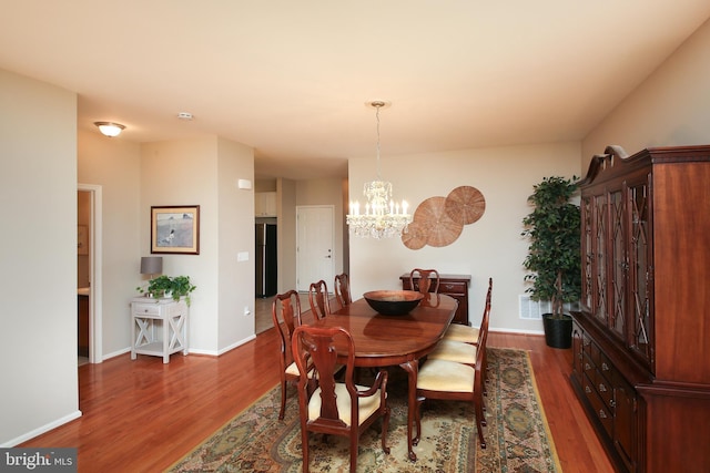 dining room with an inviting chandelier, baseboards, and wood finished floors