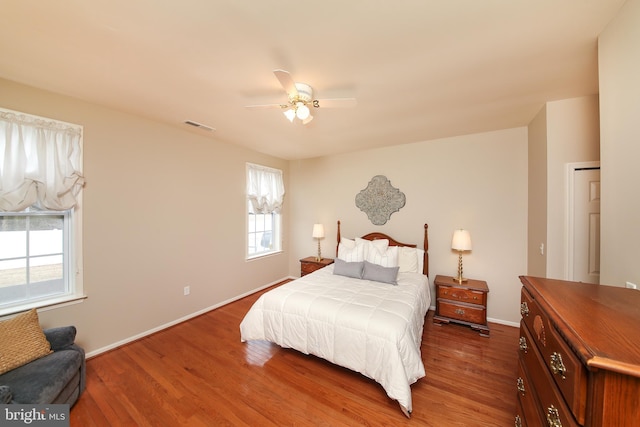 bedroom with baseboards, visible vents, ceiling fan, and wood finished floors