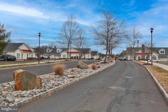 view of road featuring street lighting, a residential view, curbs, and sidewalks