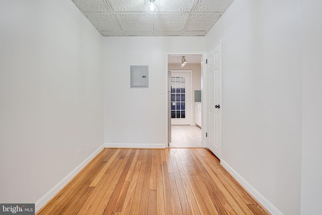 unfurnished room featuring an ornate ceiling, electric panel, light wood-style flooring, and baseboards