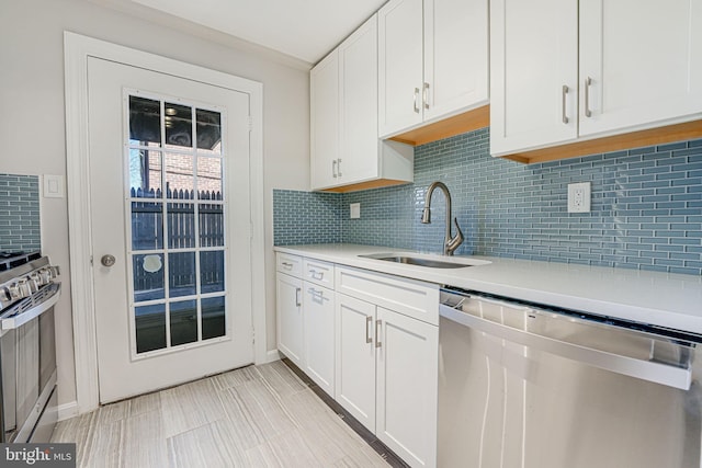 kitchen with tasteful backsplash, light countertops, appliances with stainless steel finishes, white cabinetry, and a sink