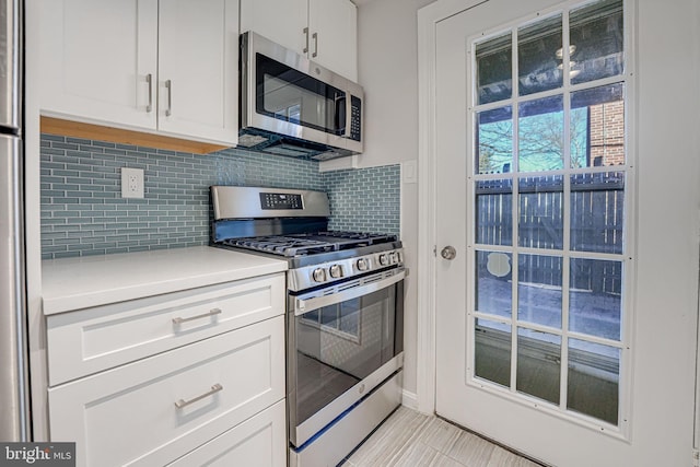 kitchen featuring stainless steel appliances, light countertops, white cabinets, and decorative backsplash