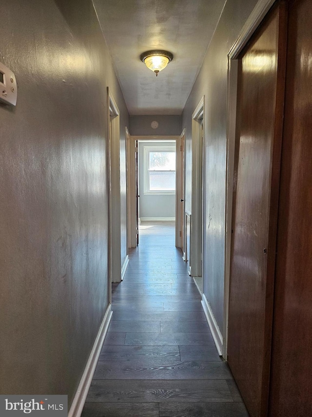 corridor with dark wood-style floors and baseboards