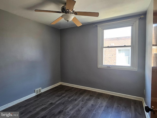 spare room with dark wood-type flooring, visible vents, baseboards, and a ceiling fan