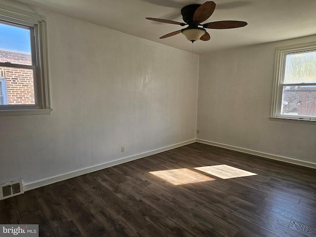 unfurnished room featuring dark wood-type flooring, visible vents, baseboards, and a ceiling fan