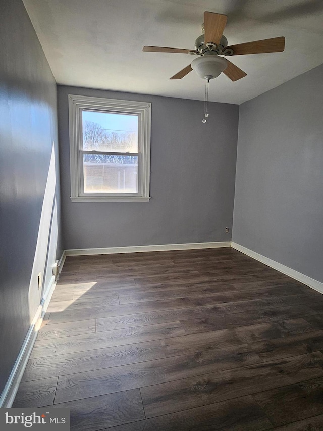 empty room with dark wood-type flooring, baseboards, and a ceiling fan