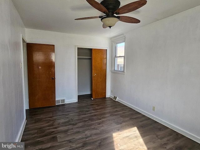 unfurnished bedroom with dark wood-style floors, baseboards, visible vents, and a closet