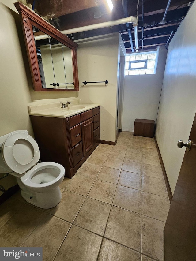 bathroom featuring baseboards, vanity, toilet, and tile patterned floors