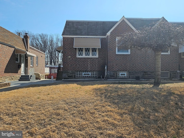 view of side of home featuring brick siding and a yard