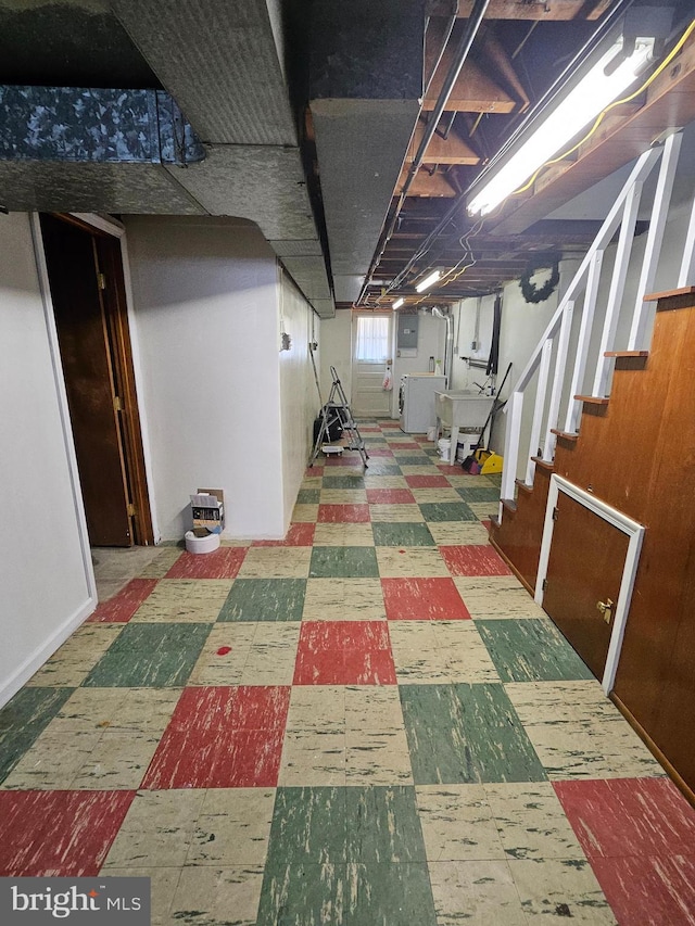 basement with tile patterned floors, a sink, washer / dryer, electric panel, and stairs