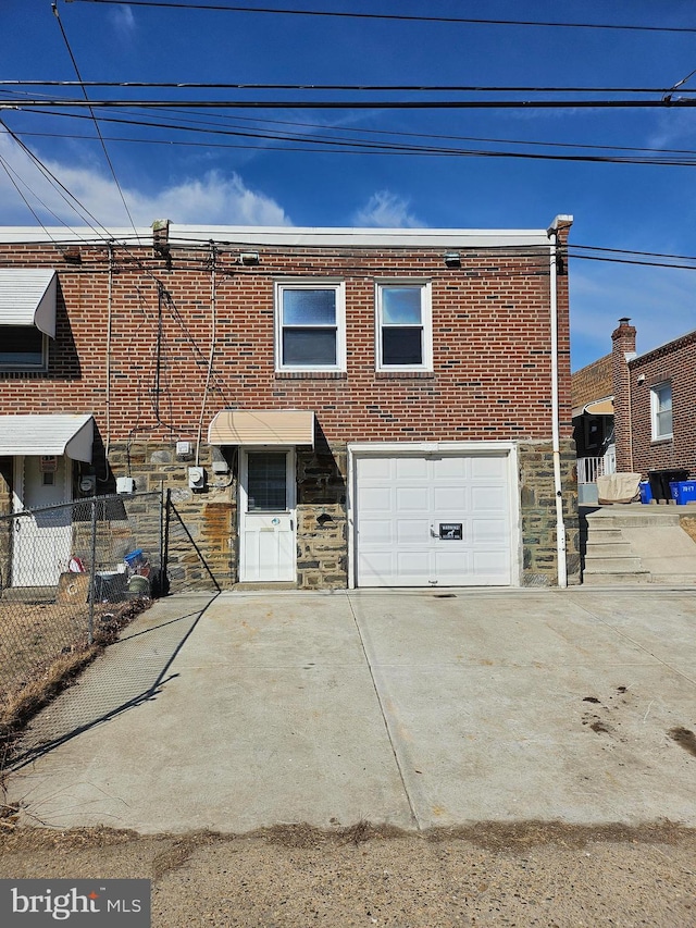 view of property with a garage, driveway, brick siding, and stone siding