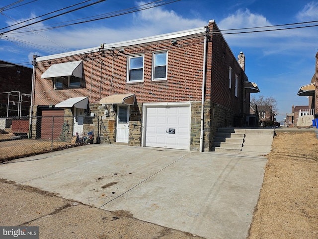 view of property featuring an attached garage, driveway, brick siding, and stone siding