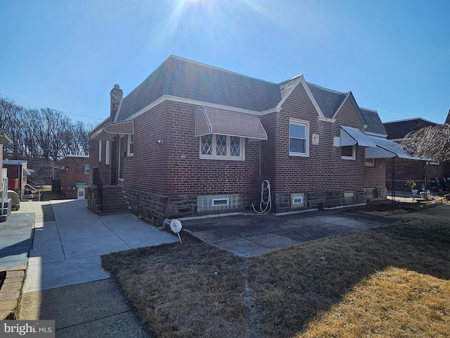 view of home's exterior with brick siding and a chimney