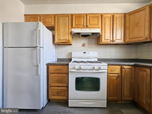 kitchen featuring under cabinet range hood, white appliances, backsplash, brown cabinets, and dark countertops