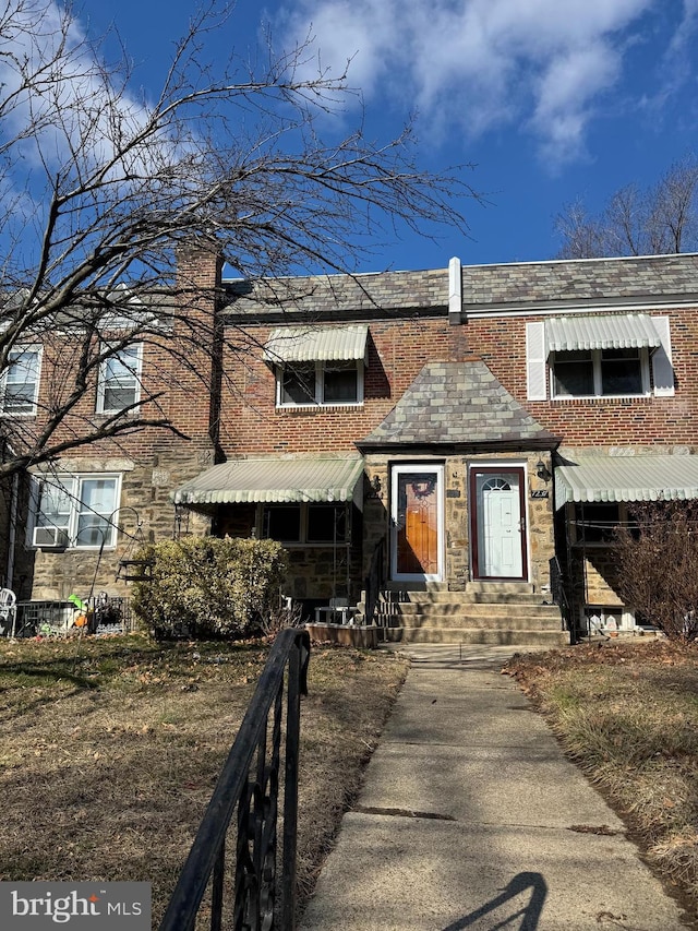 view of property featuring entry steps, brick siding, and cooling unit