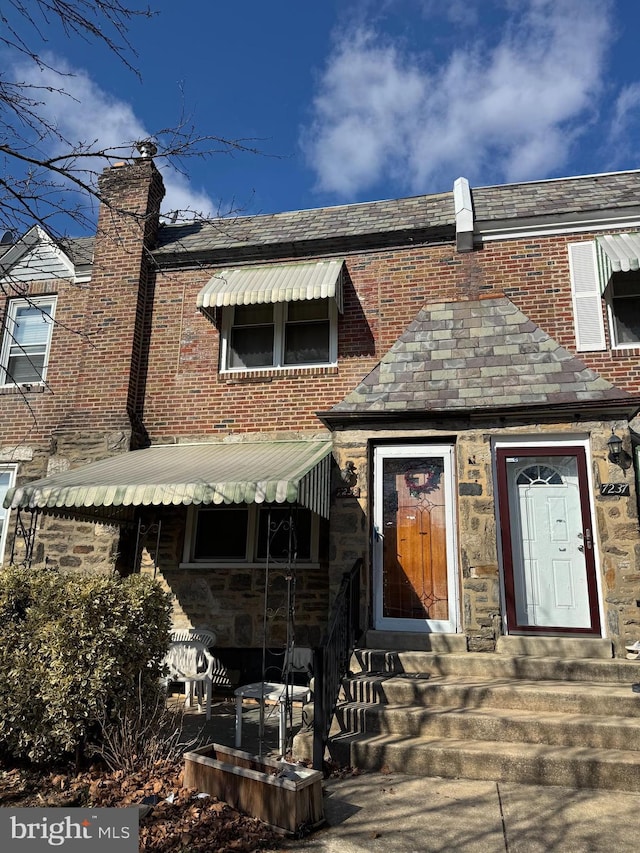 back of house featuring entry steps and stone siding