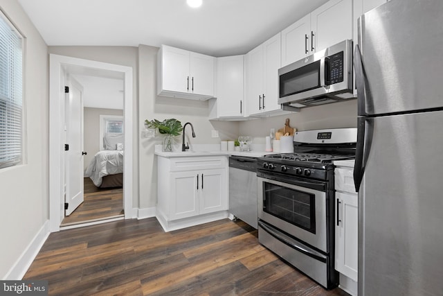 kitchen with stainless steel appliances, a sink, white cabinets, light countertops, and dark wood-style floors