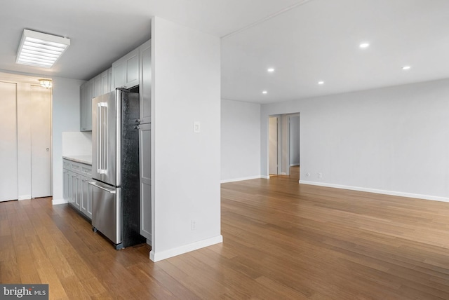 kitchen with light wood finished floors, baseboards, open floor plan, light countertops, and high end fridge