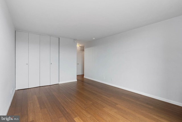 unfurnished bedroom featuring a closet, baseboards, and wood finished floors