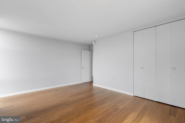 unfurnished bedroom with light wood-style flooring, baseboards, and a closet